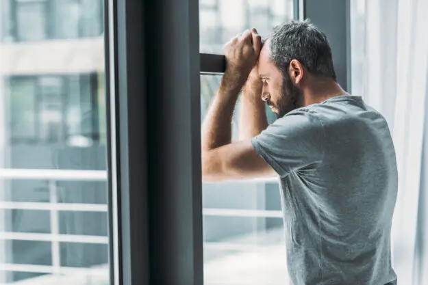 Suicidal Thoughts – What They Are and How You Should Respond a person leans against a window wondering what are suicidal thoughts