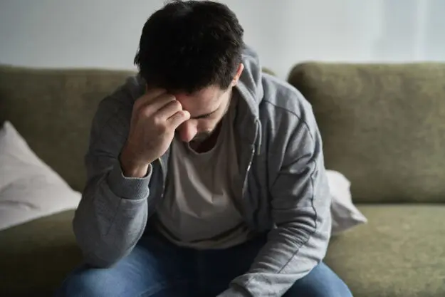 Do I Need Antidepressants a person sits on a couch putting their head in their hands wondering do i need antidepressants