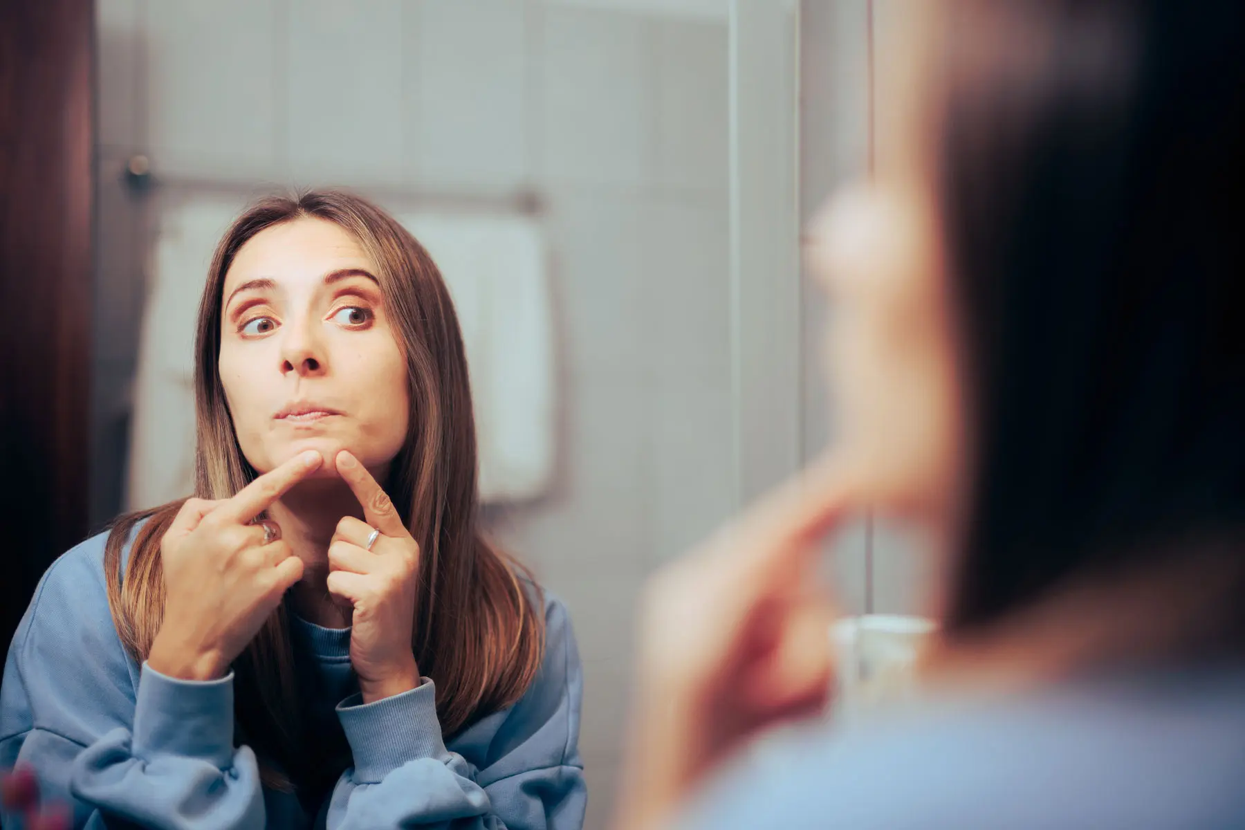 Is Skin Picking a Form of Self-Harm a person picks their skin in a mirror while wondering is skin picking a form of self harm