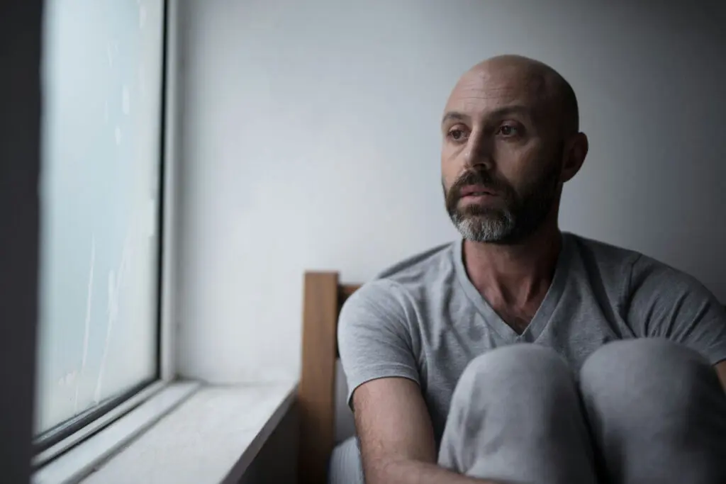 Person reflecting alone, representing the emotional challenges of depression and the need for professional support.