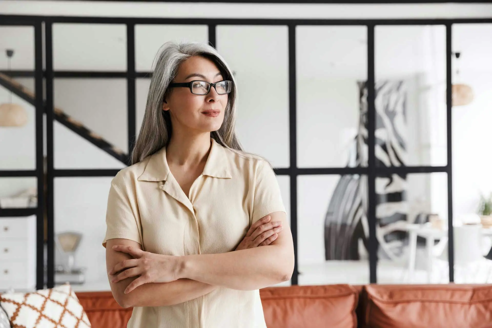 Middle-aged woman standing peacefully by a window, reflecting during the menopausal transition.