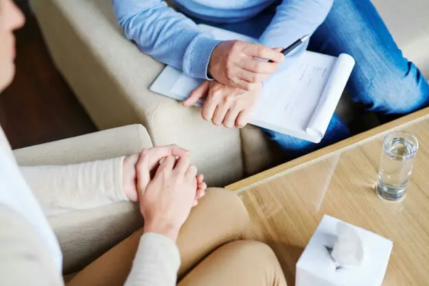 Therapist guiding a client through cognitive behavioral therapy techniques in a private session