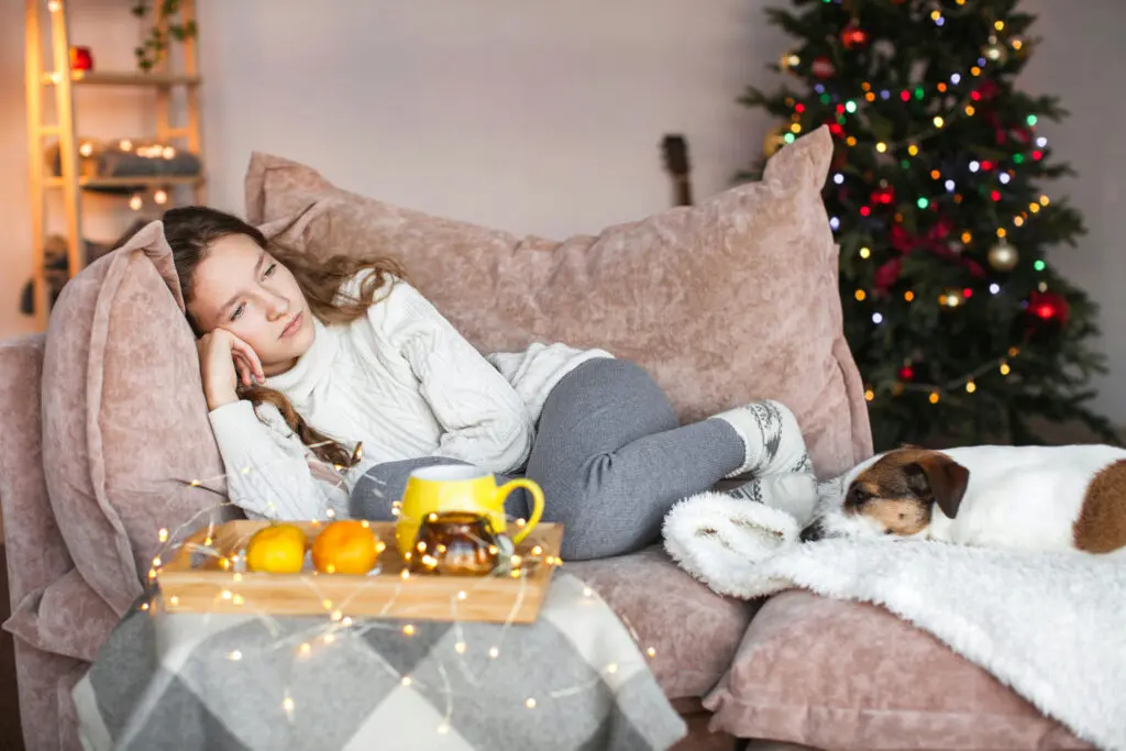 Person resting on a couch with low energy, illustrating common signs of holiday loneliness like fatigue and sadness.