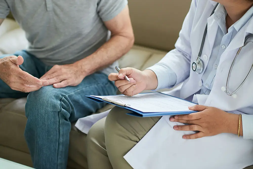 man sitting on a couch discussing anxiety symptoms with doctor