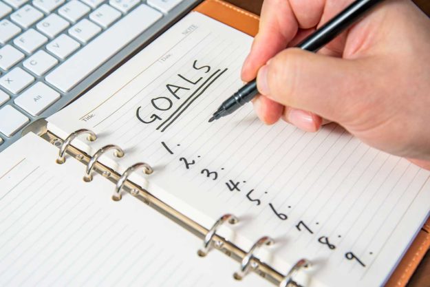 person writing down realistic new years goals