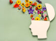 flowers coming out of a wooden head cutout to show mental health awareness month