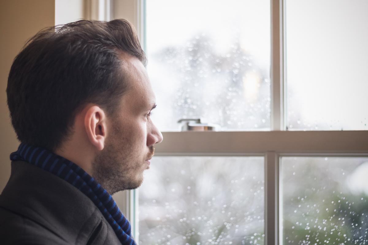 person looking out window dealing with seasonal affective disorder