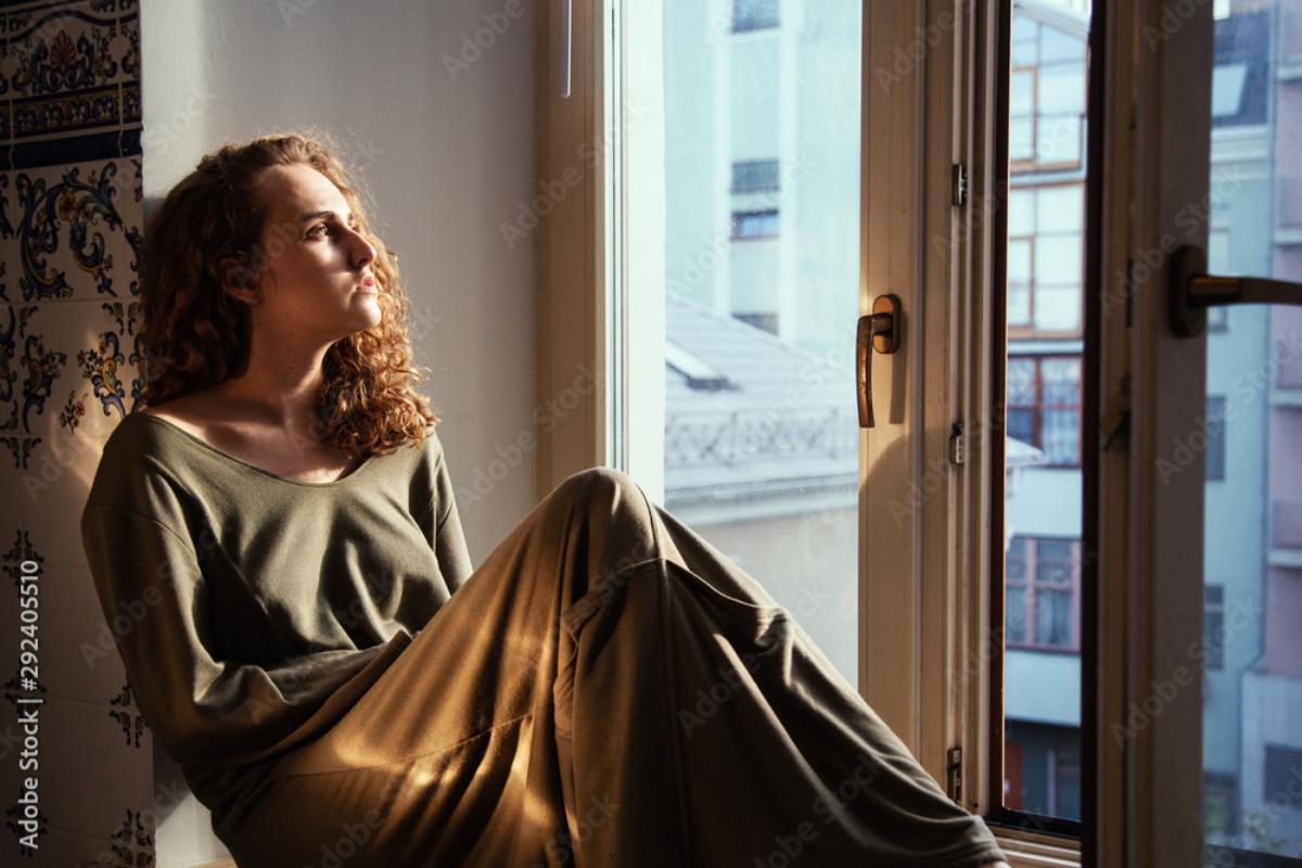 person sitting looking out window dealign with seasonal depression