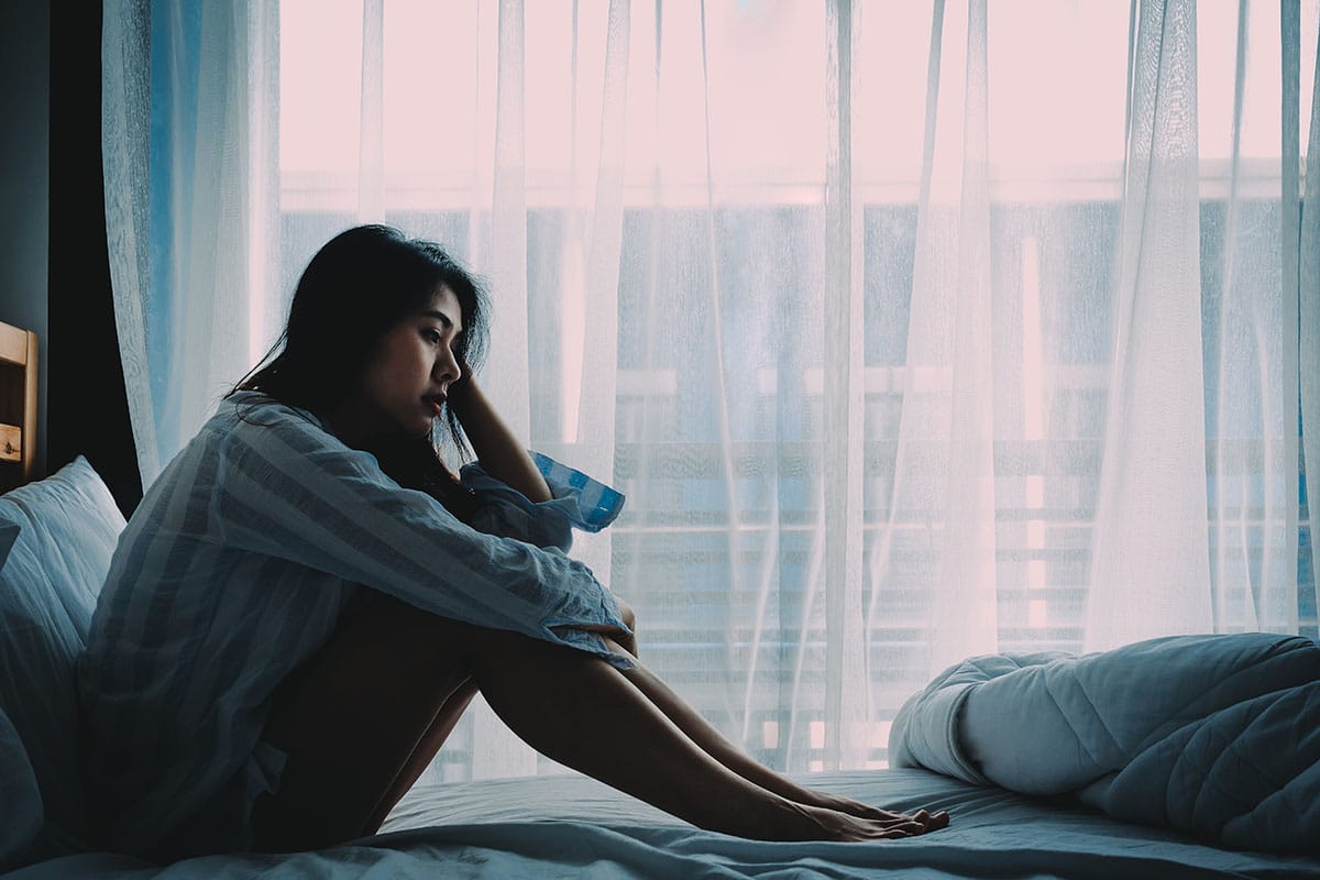 a woman sitting on her bed considering if she needs bpd treatment program