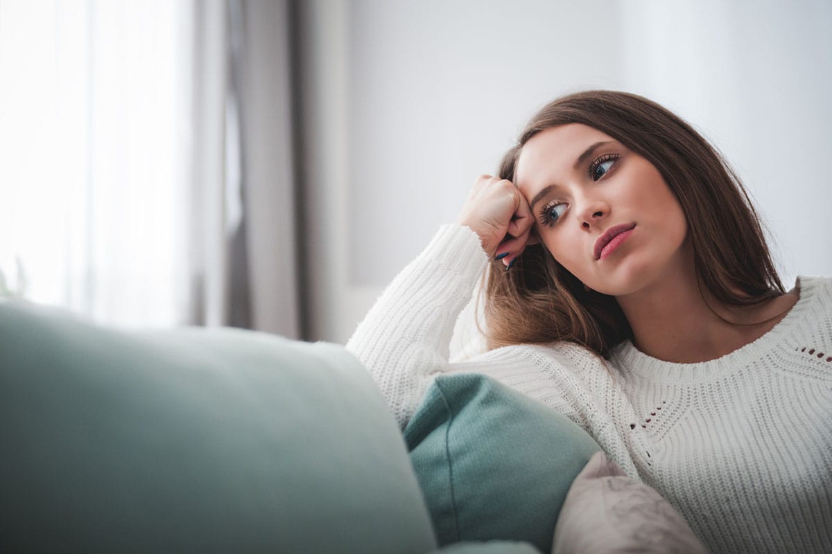 woman sitting on her couch leaning on her arm thinking about world bipolar day