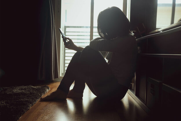 a woman scrolls on her phone while seeming to be upset