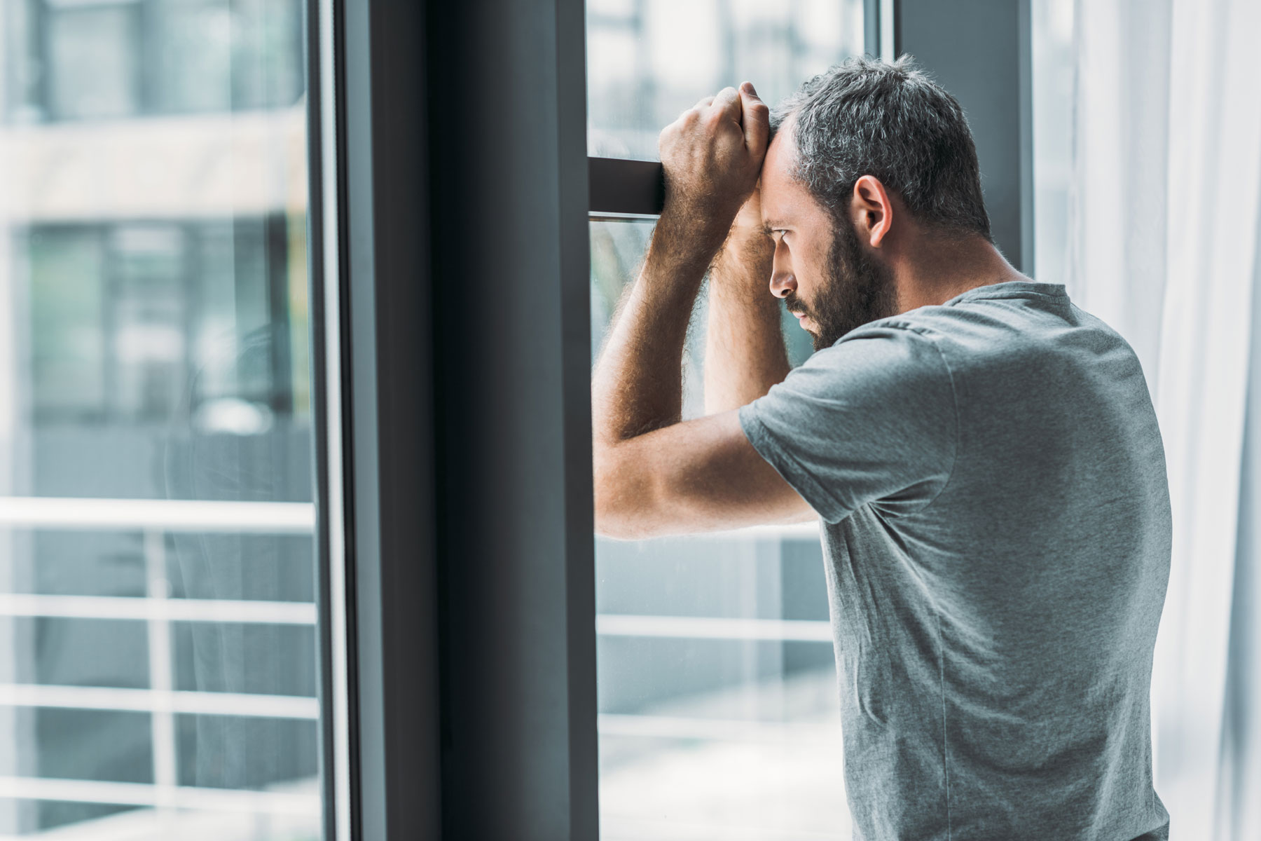 a person leans against a window wondering what are suicidal thoughts