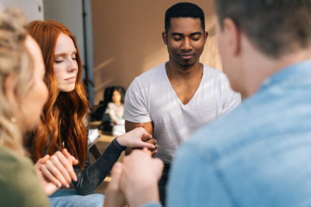 individuals in group therapy for mental health meditate together as part of their holistic treatment