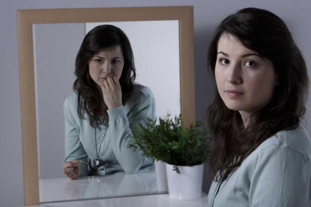a woman struggles with split personality disorder as portrayed by a different reflection in a mirror