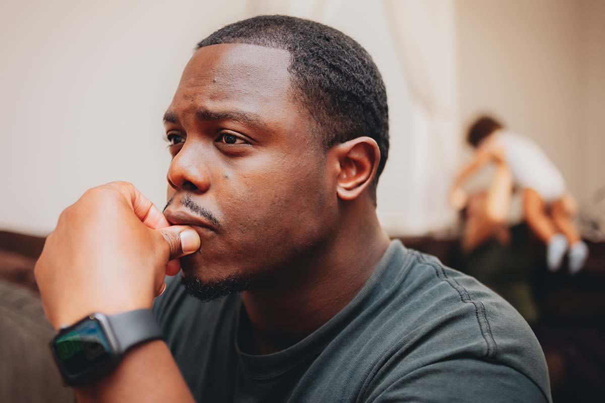 a person sits thinking while their family is in the background blurred to show substance abuse in military families