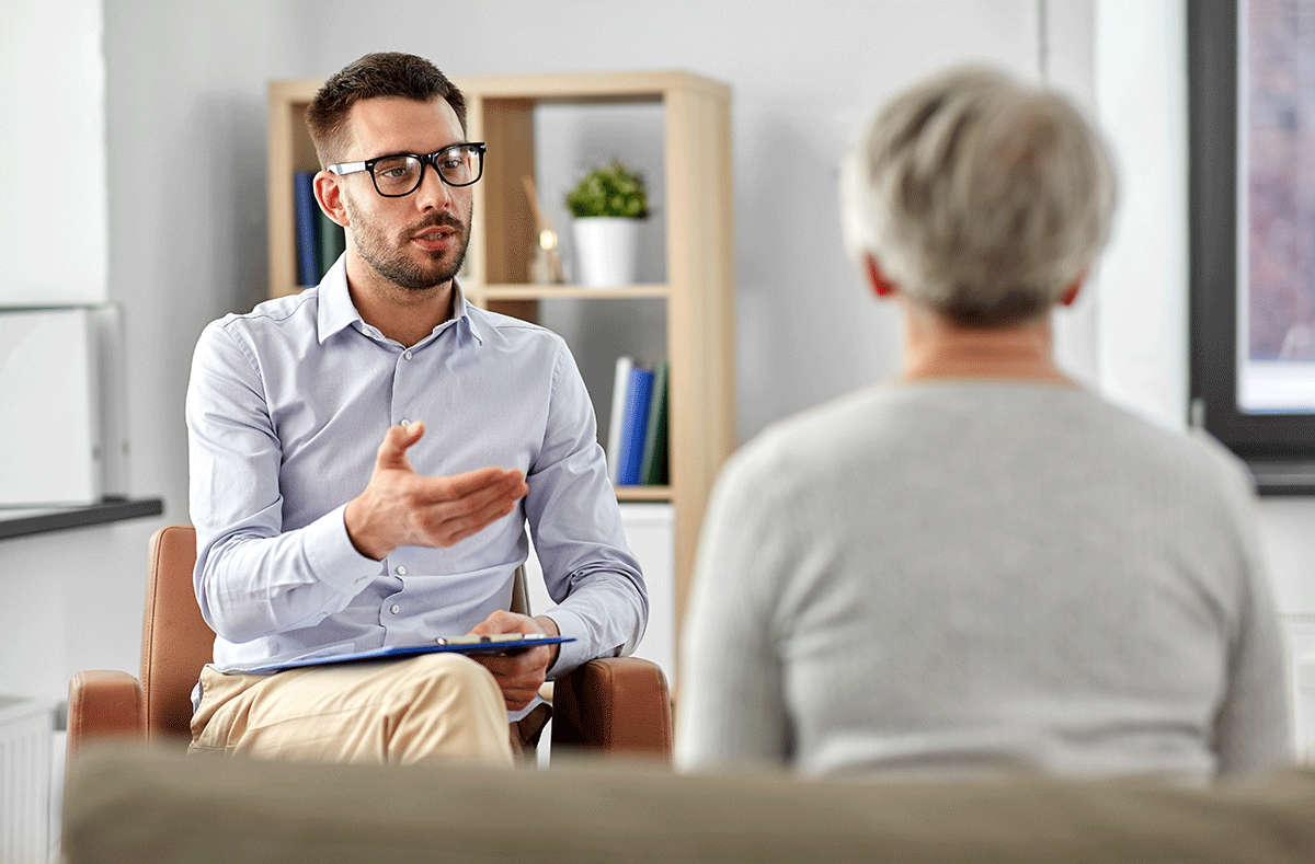 a person with glasses talks to a person sitting on a couch about dialectical behavior therapy techniques