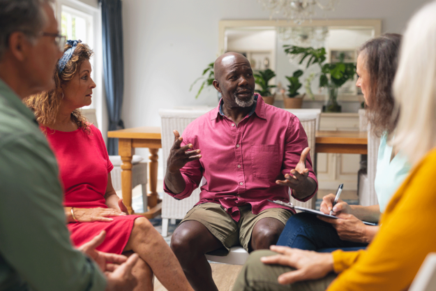 a group of people sit in chairs in a circle and discuss the benefits of family support groups