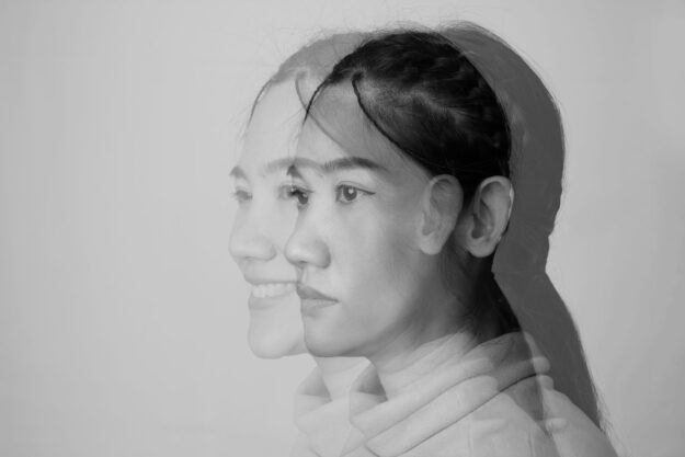 an image of a person looking sad overlayed with an image of them looking happy as they ponder "what are dissociative disorders?"