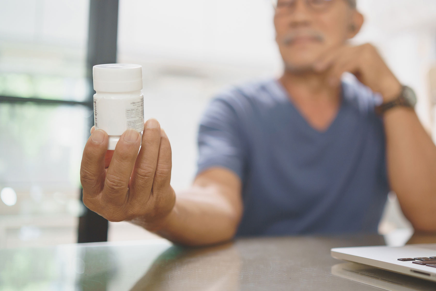 a person holds a bottle of prescription medication while wondering "what is medication management?"