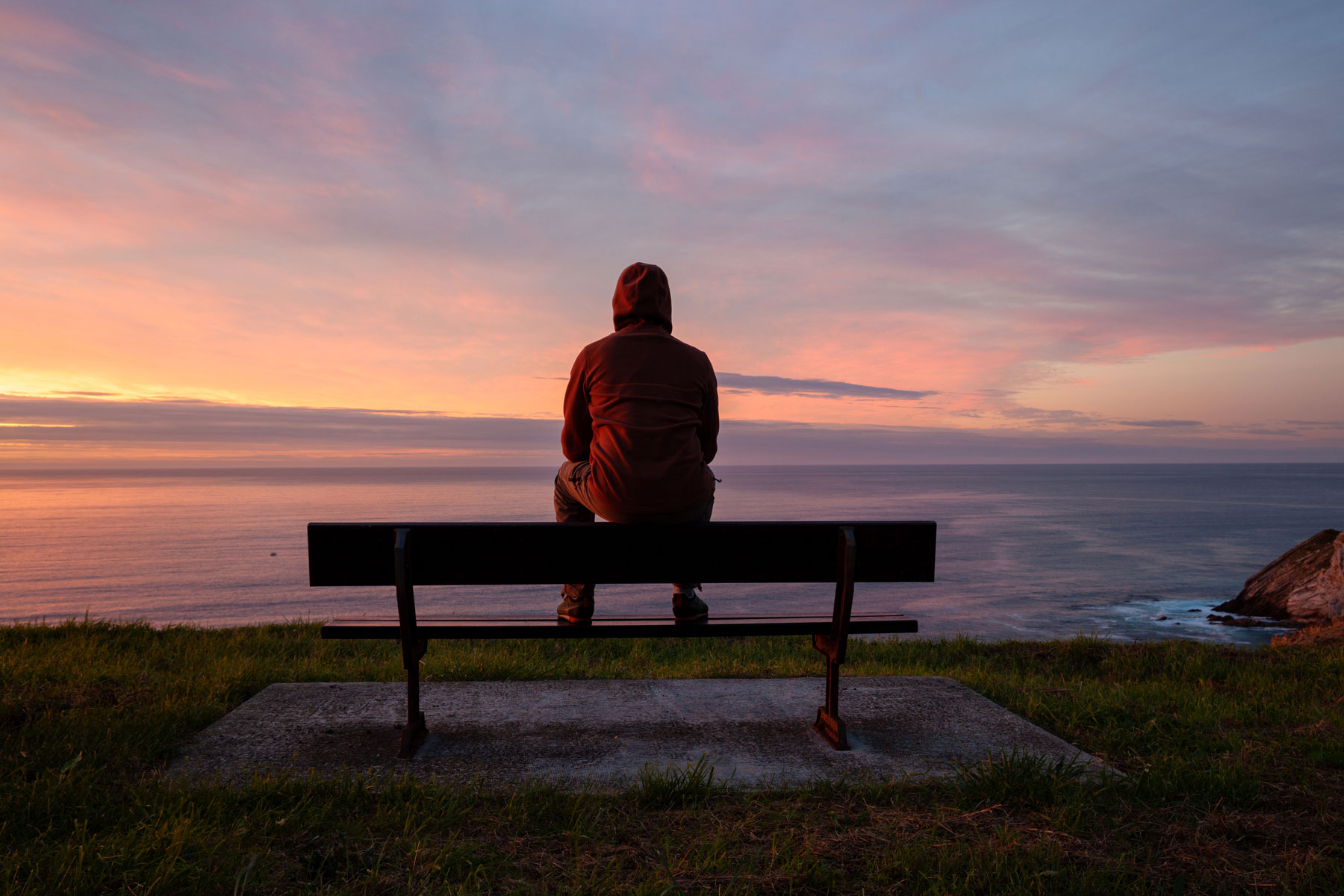 a man feels lonely to the point of it affecting his mental health as he sits alone on a bench at dusk