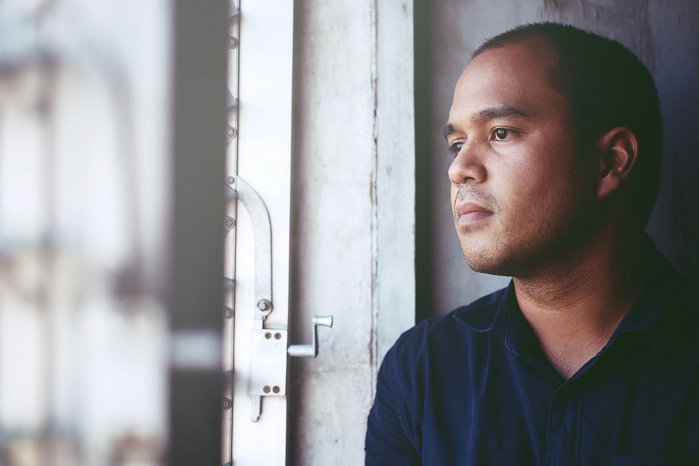  Person looking thoughtfully out a window, representing social withdrawal and emotional isolation common in schizophrenia.