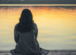 Person sitting quietly outdoors reflecting while coping with grief and loss after a life change.
