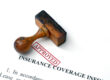 A wooden stamp rests beside a red "Approved" mark on a document titled Insurance Coverage.